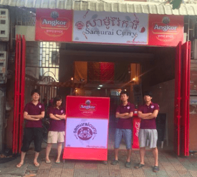 カンボジアのサムライカレーの店構え、メンバー４人が腕を組んで写真に映る