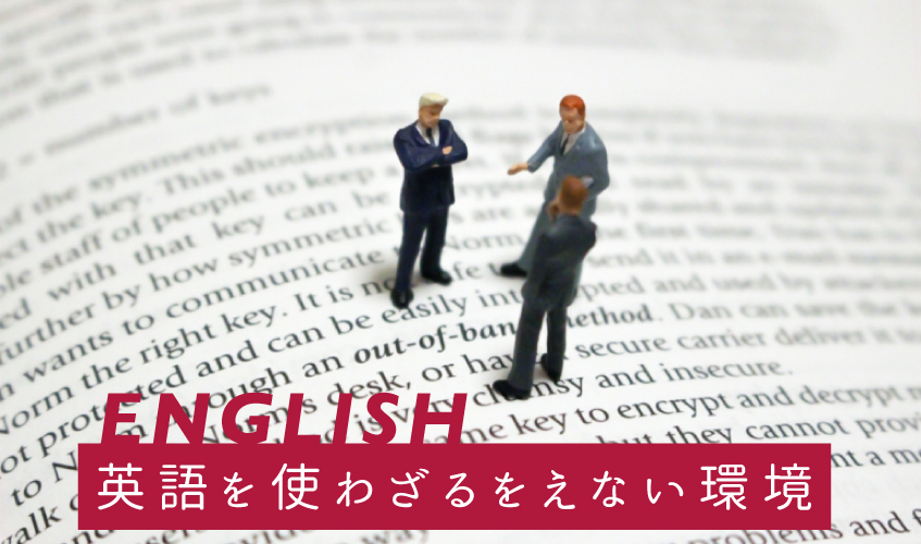 「English　英語を使わざるをえない環境」英文の印刷物の上で小人が話し合っているイメージ写真