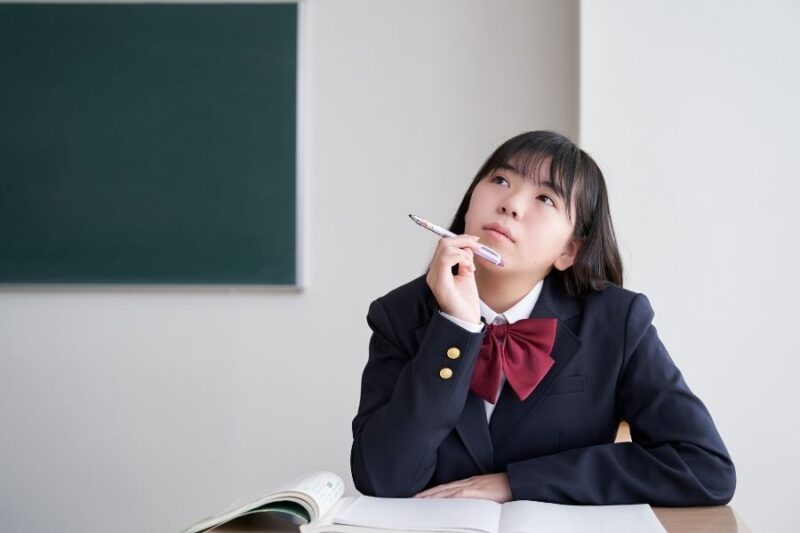 高校生が教室のデスクで考える様子