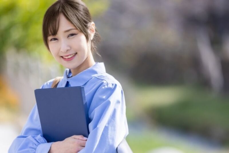 ファイルを手にして微笑む学生