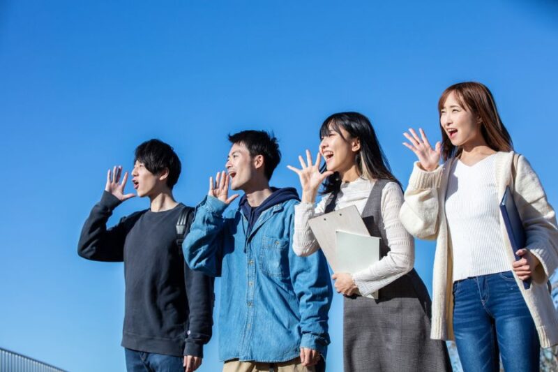 学生４名が青空の下で楽しそうに叫ぶ様子