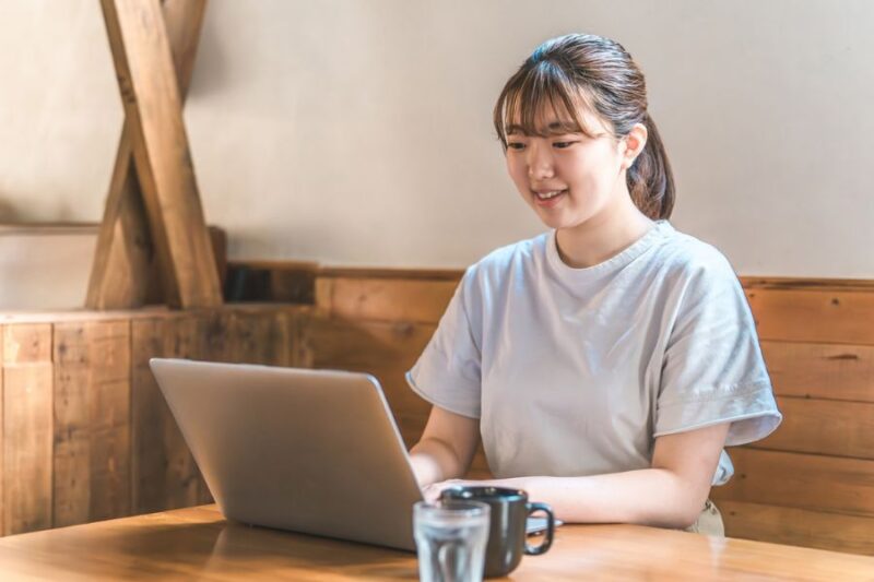 室内でパソコンを使用する若い女性の様子