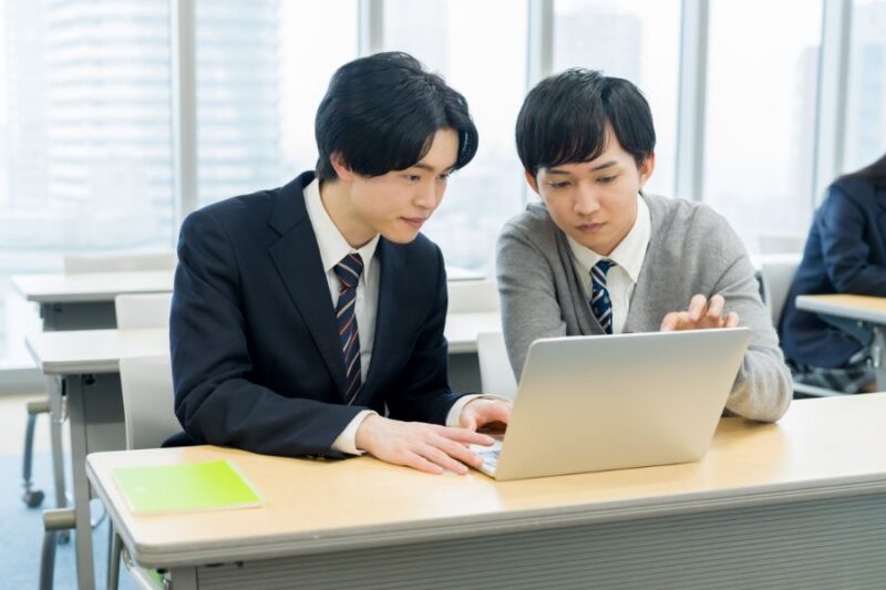 男子高校生がパソコンを前に相談する様子