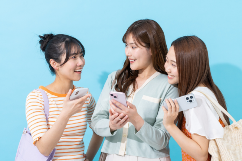 携帯を手に持ち会話する女性３名