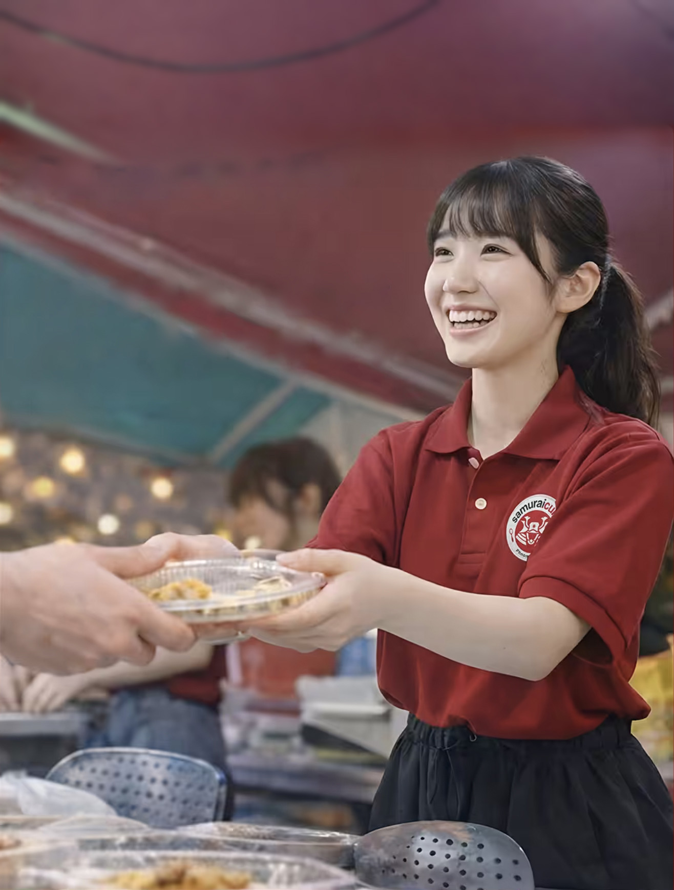 カンボジア・プノンペンの夜市で、来店客に料理を手渡す高校生プログラム参加者