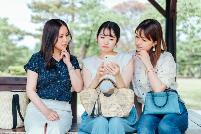 スマホを見ながら悩む3人の女性