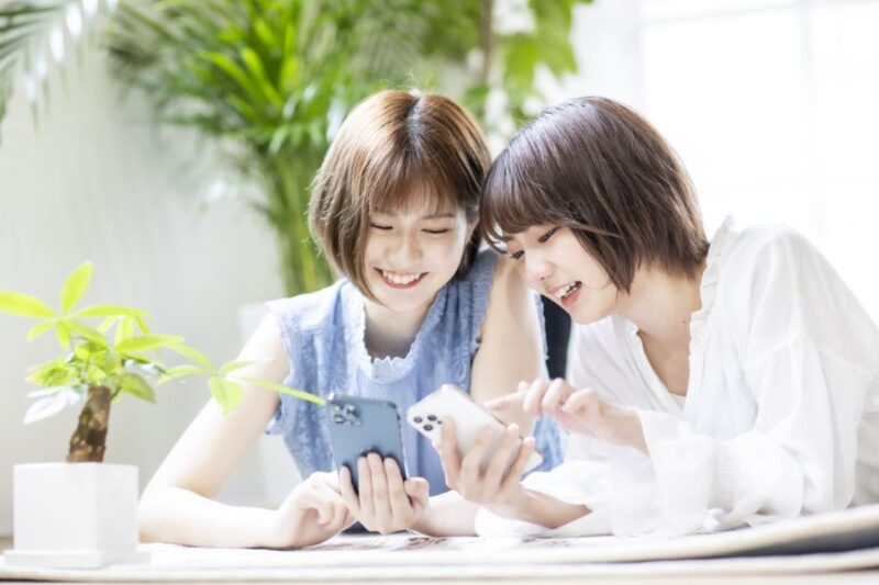 スマホを見ながら談笑する女性2名
