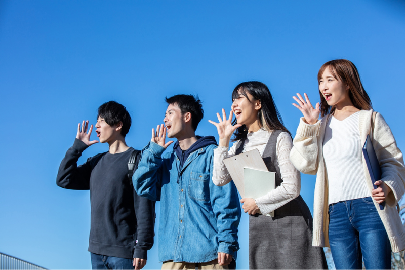 学生４人が校舎の屋上でにこやかに叫ぶ様子